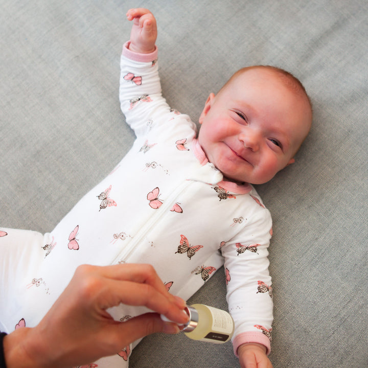 baby smiles at person holding lavender baby oil 