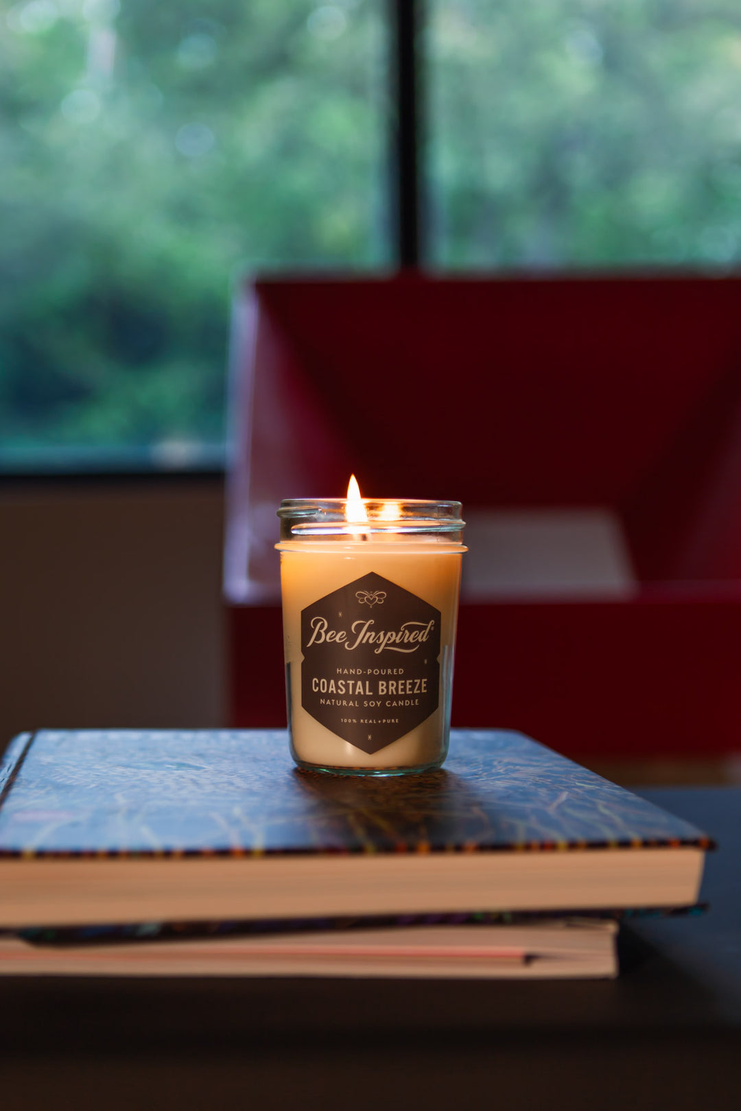 Coastal Breeze jelly jar candle burning on stack of books 