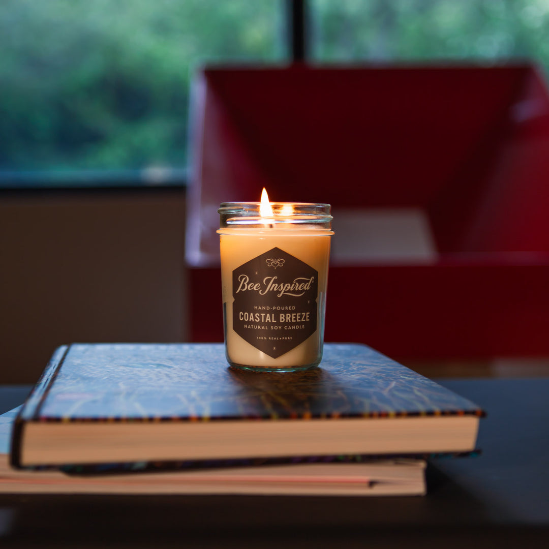 Coastal Breeze jelly jar candle burning on stack of books 