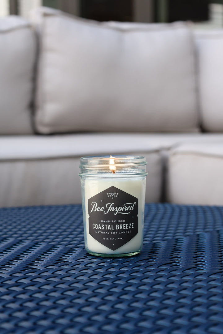 Coastal Breeze jelly jar candle burning on blue table 