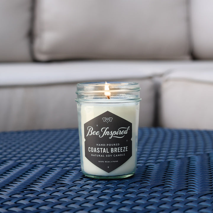 Coastal Breeze jelly jar candle burning on blue table 