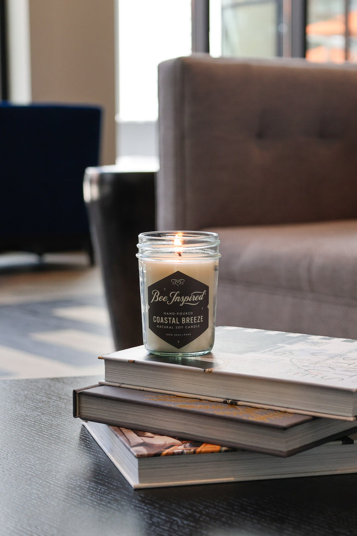 Coastal Breeze jelly jar candle burning on stack of books 