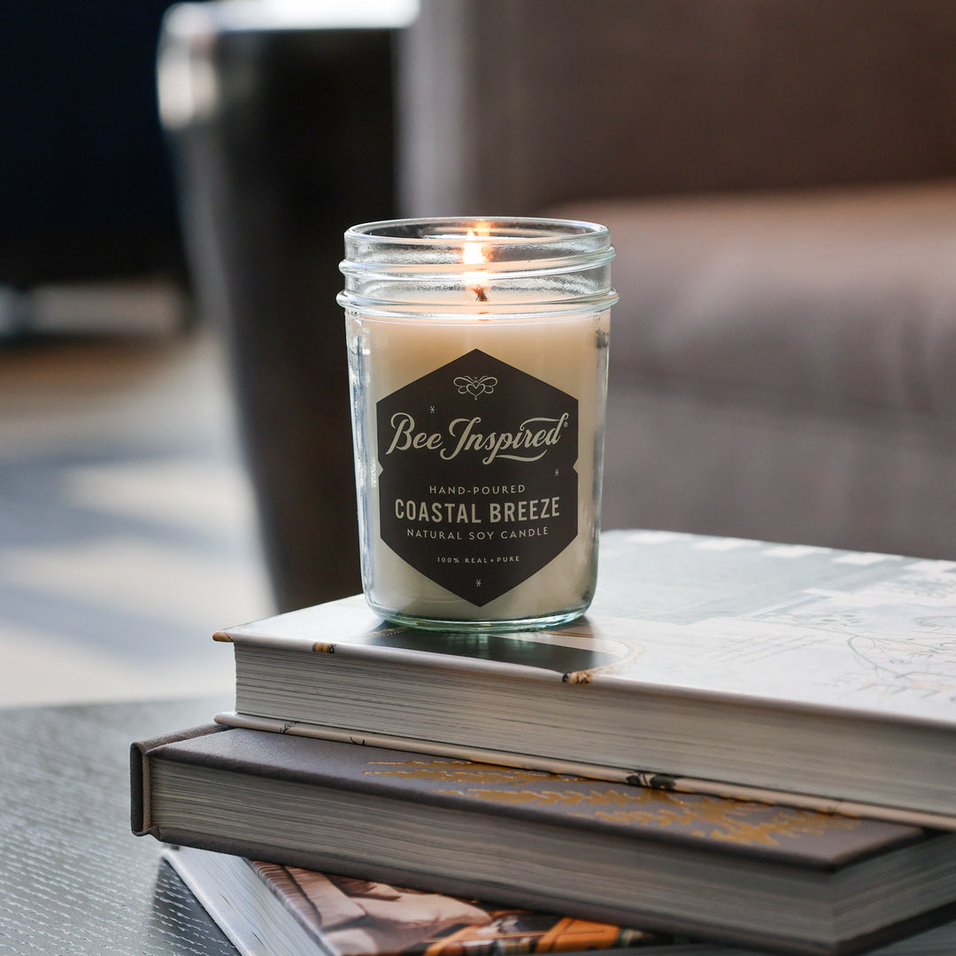 Coastal Breeze jelly jar candle burning on stack of books 