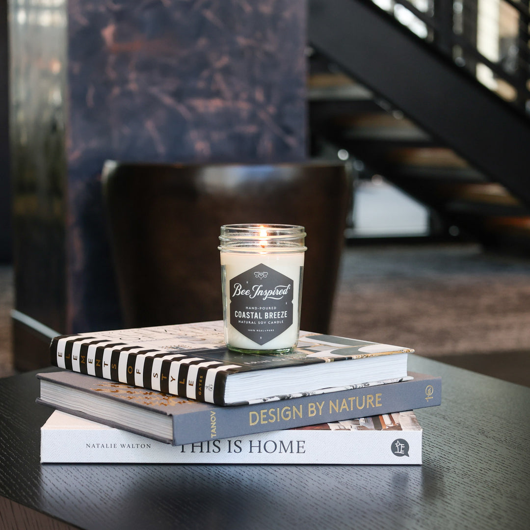 Coastal Breeze jelly jar candle burning on stack of books 