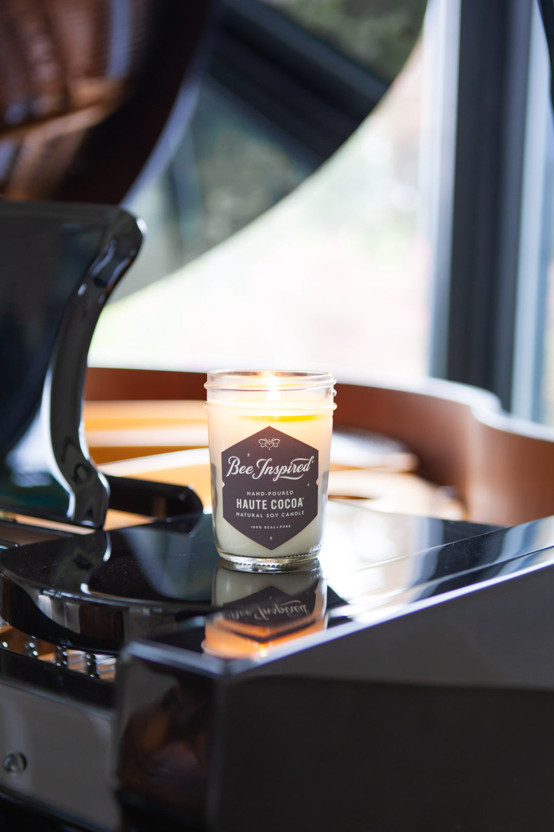 Haute Cocoa jelly jar candle burning on top of piano