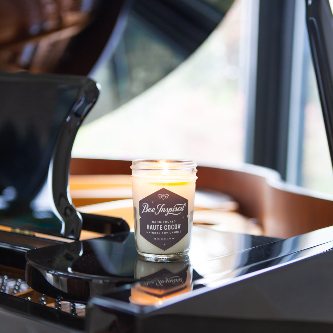 Haute Cocoa jelly jar candle burning on top of piano