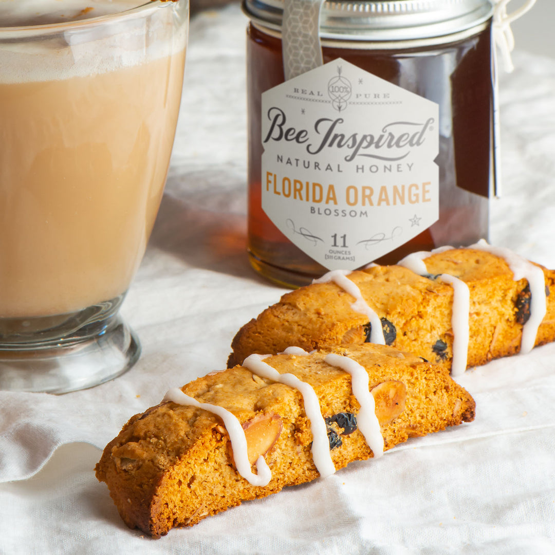 Glazed honey orange biscotti next to Florida Orange honey and mug of coffee 