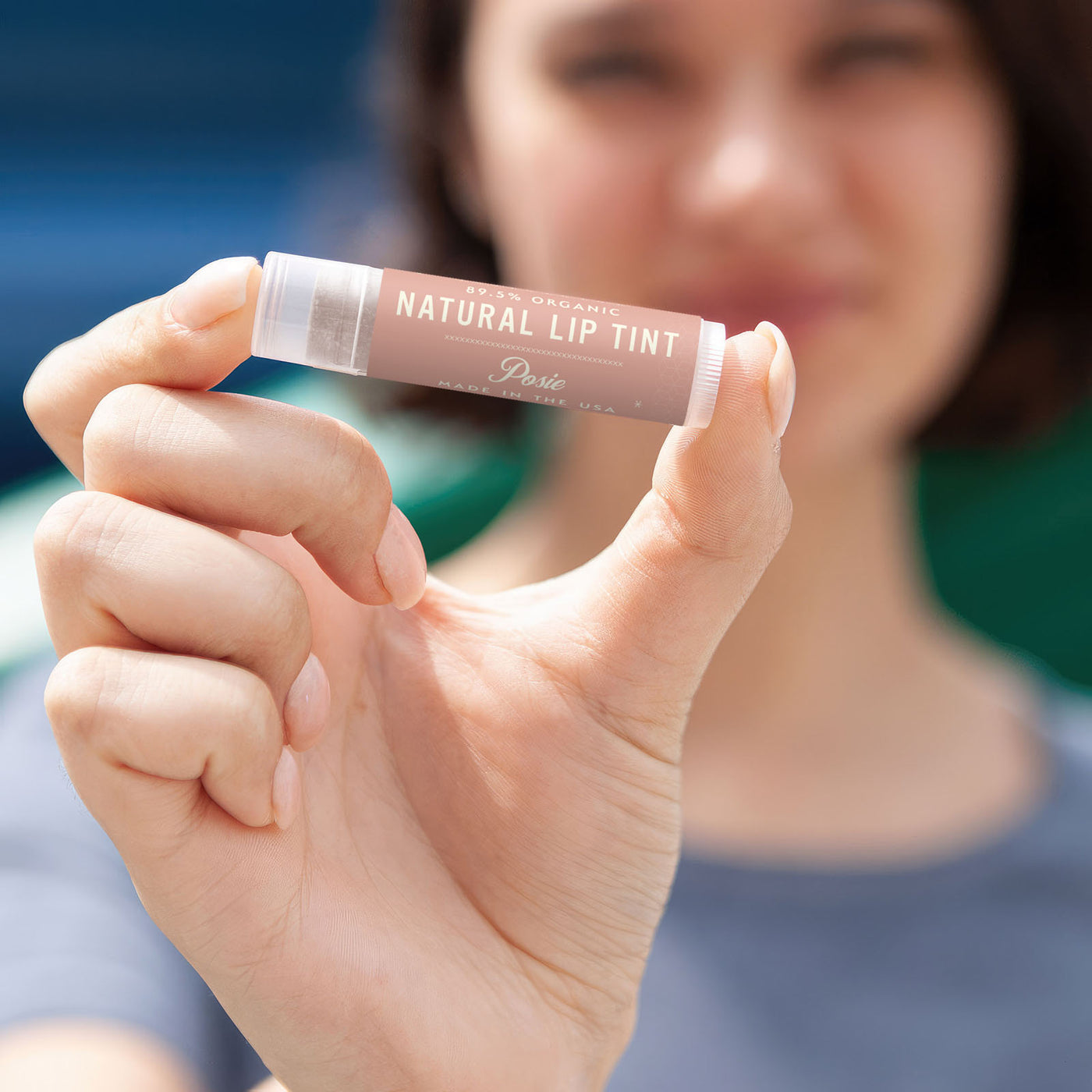 Woman holds Posie lip tint towards the camera 