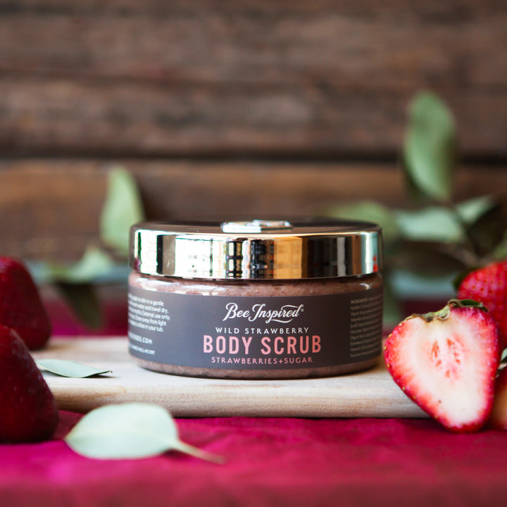 Wild Strawberry body scrub displayed with fresh strawberries 