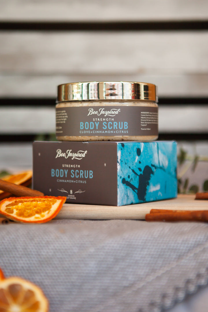 strength body scrub from bee inspired honey retail store in owings mills on top of its box with orange slices 