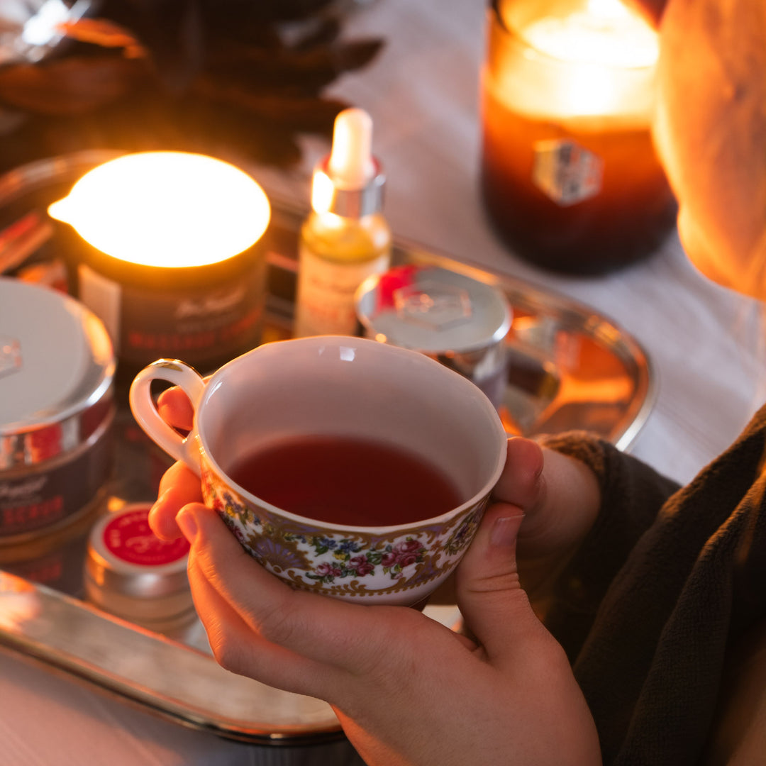 Woman holds mug of tea next to Rose Garden display 