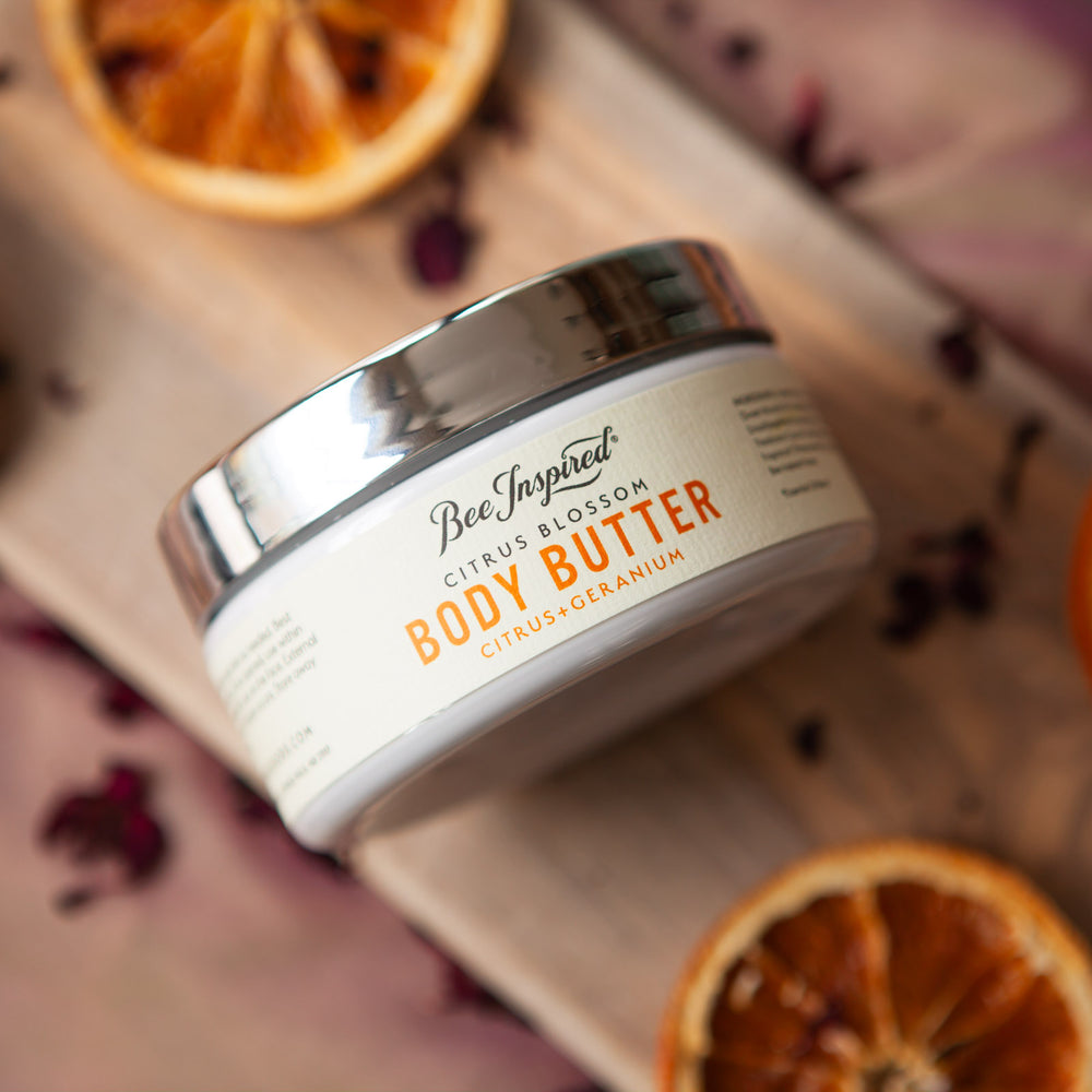 citrus body butter on wood with geranium petals