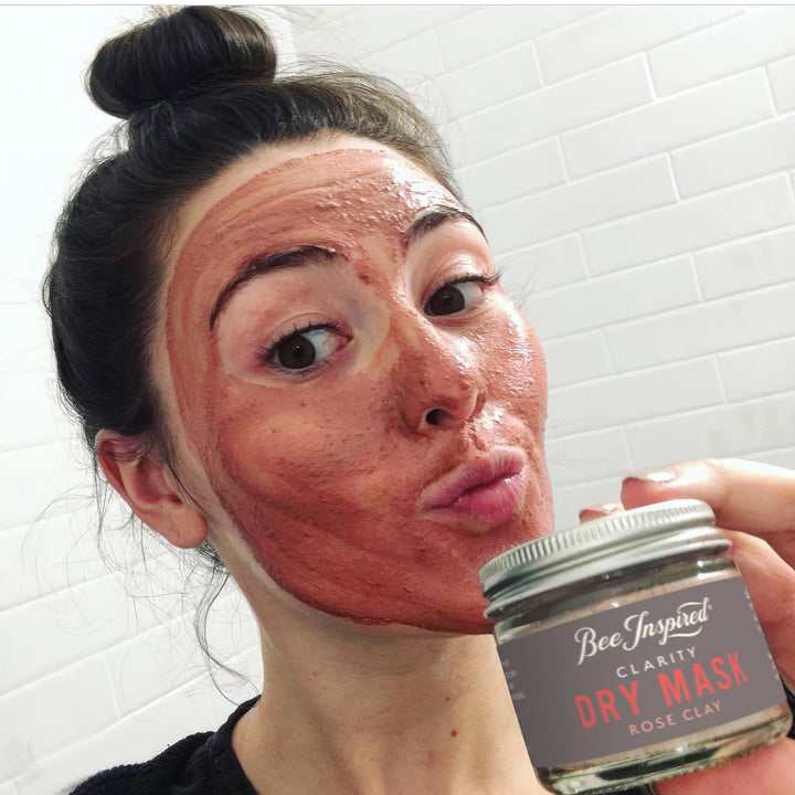 Woman wearing Clarity face mask holds jar of dry mask 