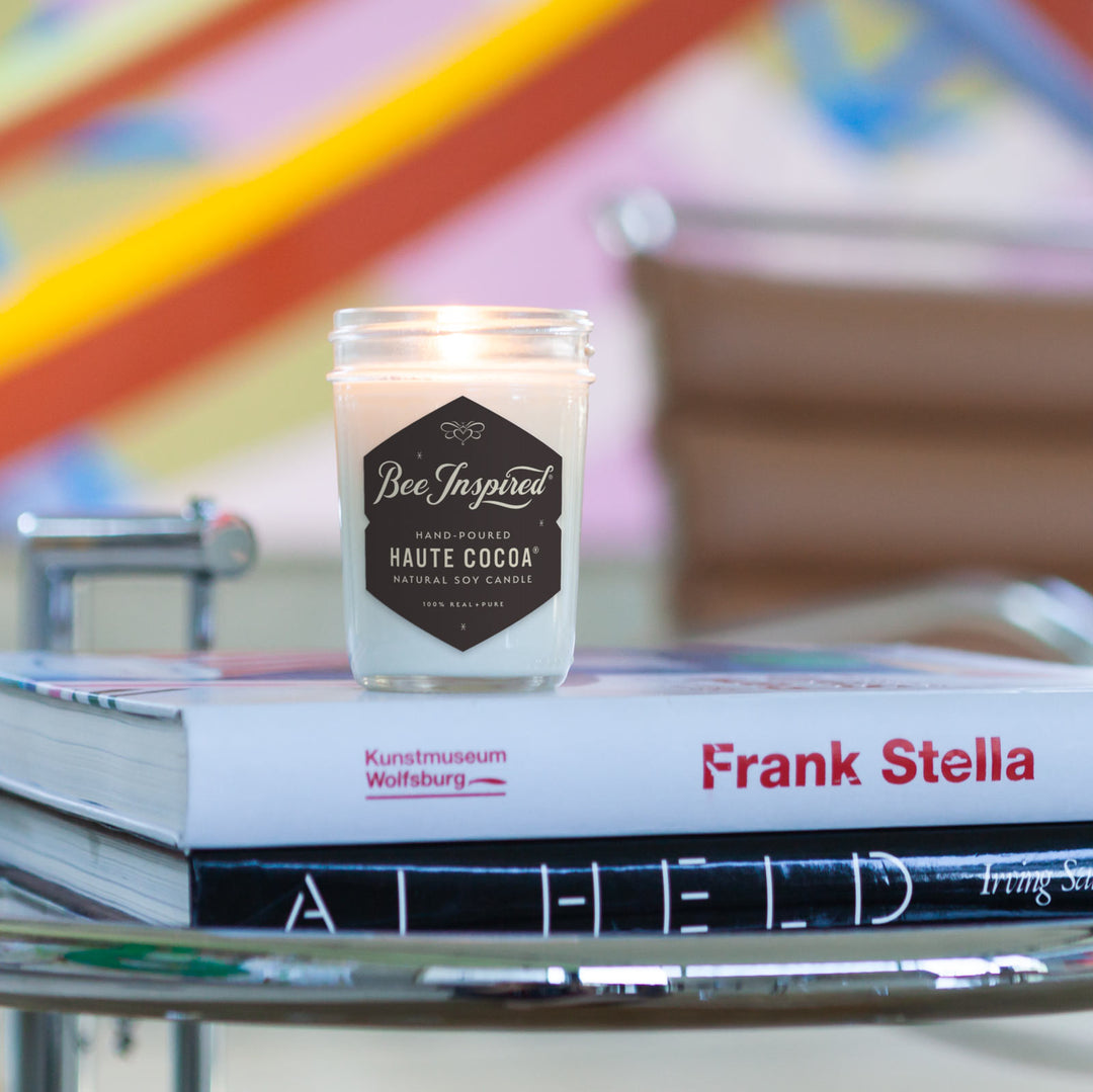 Haute Cocoa jelly jar candle burning on stack of books 