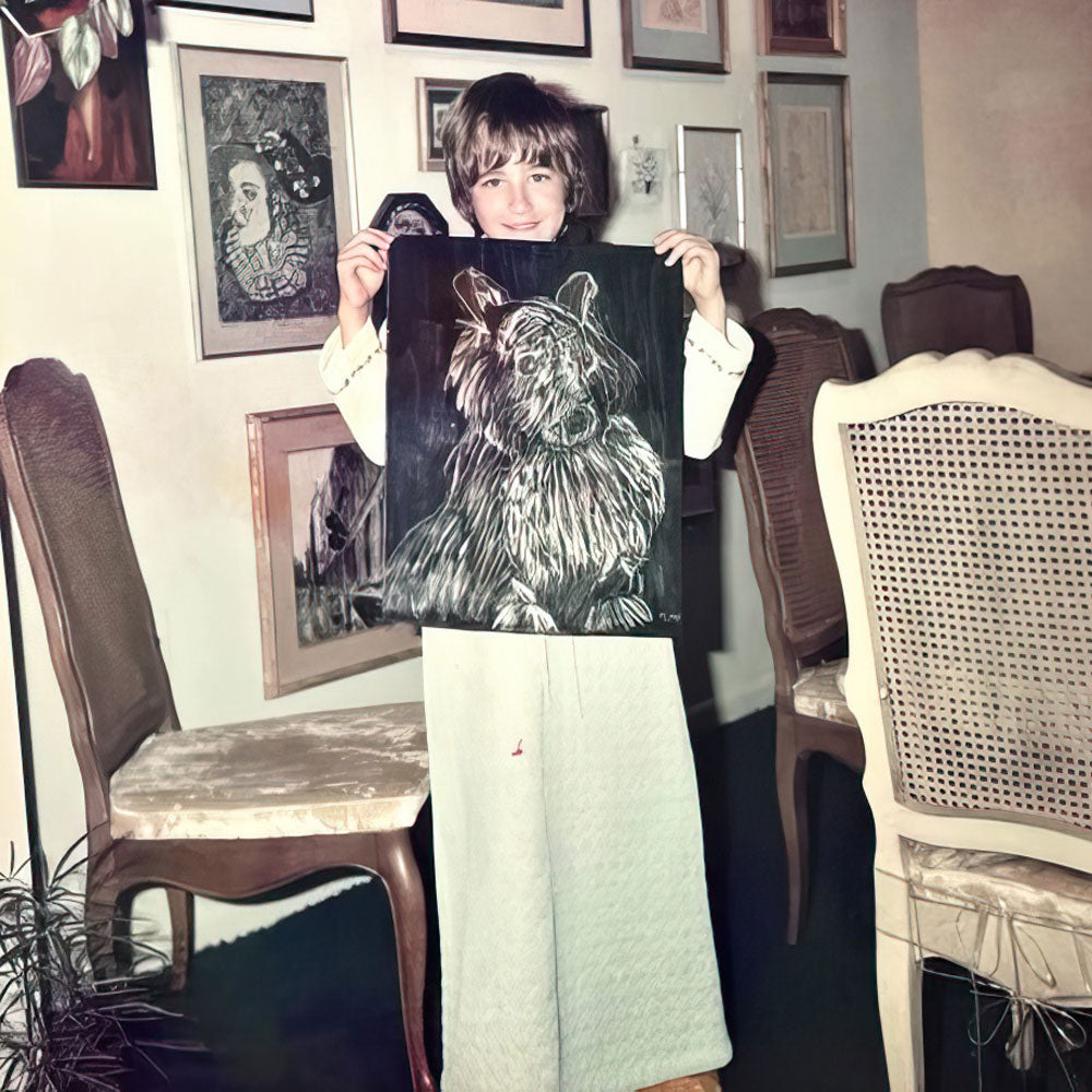 Young Kara holding a drawing of a dog in front of framed drawings 