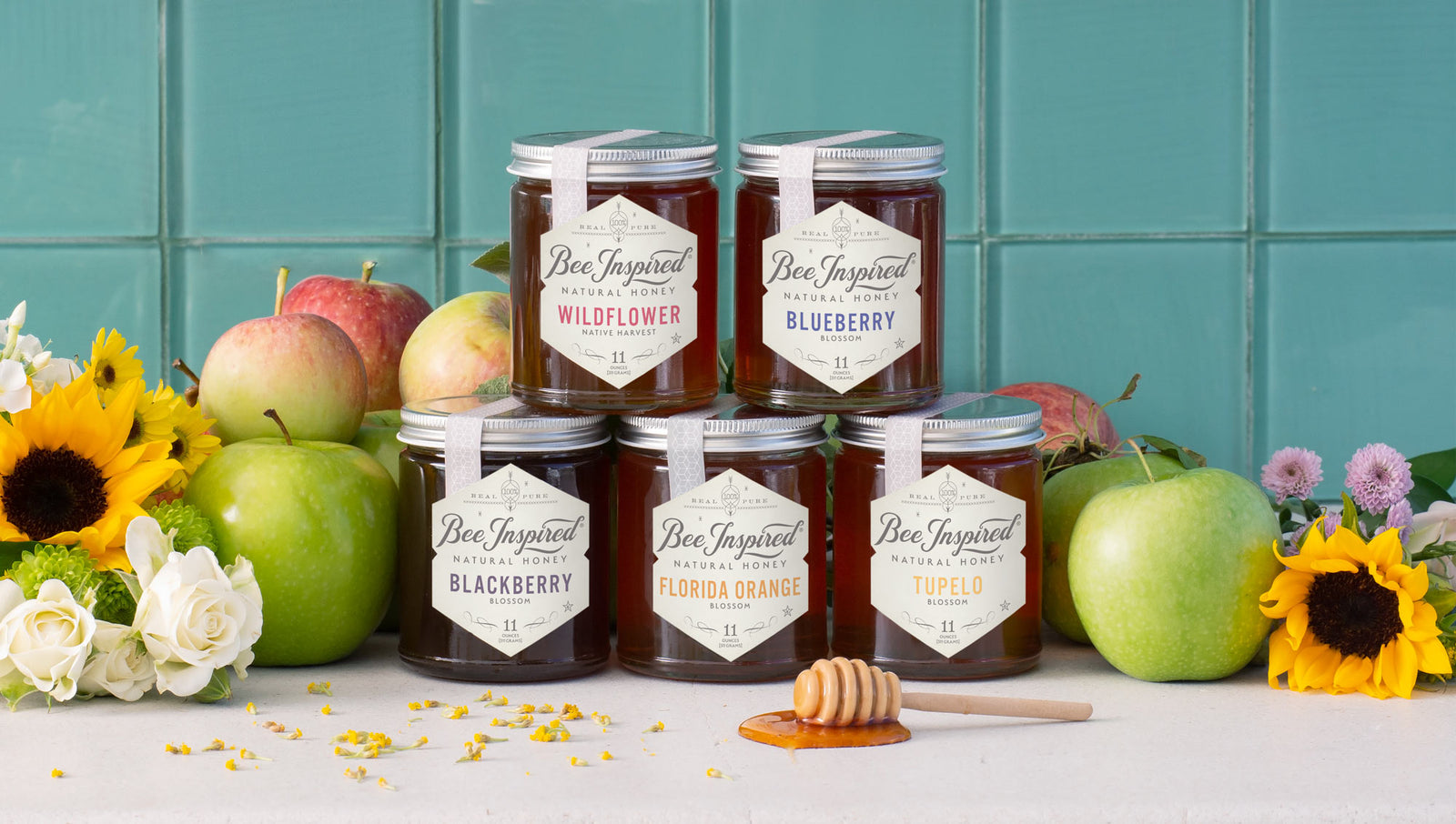 Tower of different honey jars in front of apples 