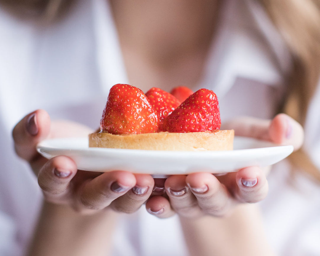 Person serves a plate with a pastry and strawberries 