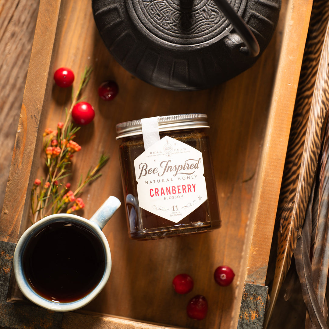 Cranberry honey next to tea mug and cranberries 